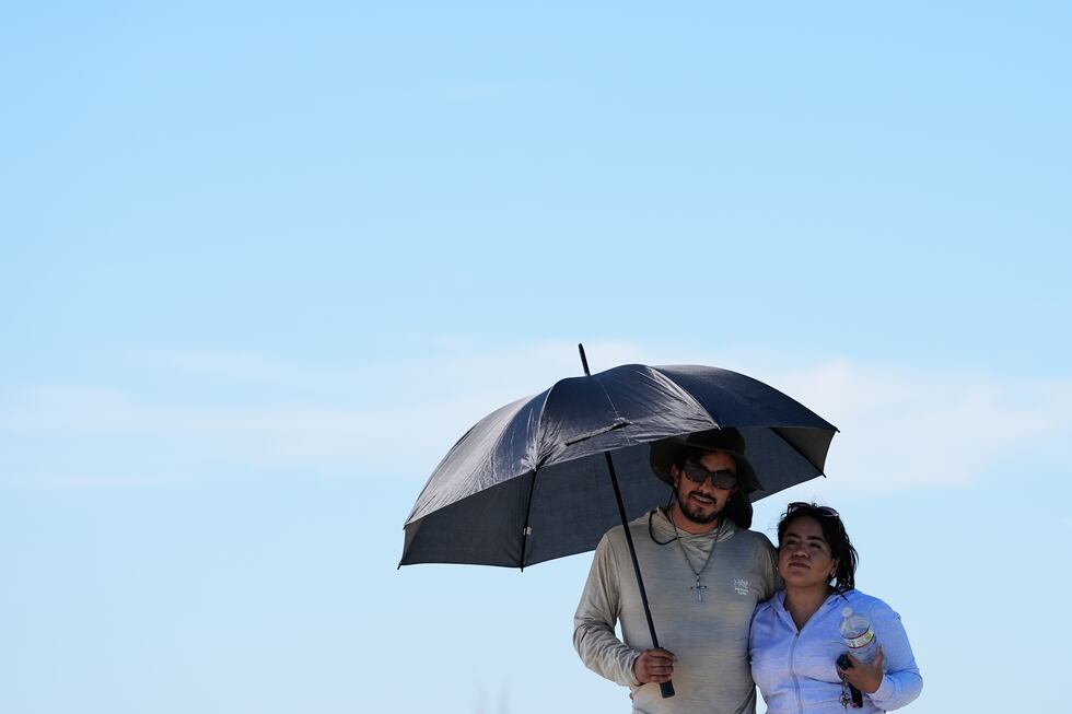 ARCHIVO - Juan Olmedo, a la izquierda, y su esposa Alejandra Delgado se protegen del sol con...
